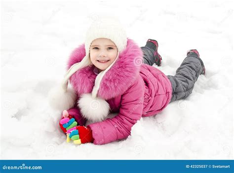Cute Smiling Little Girl Lying On Snow In Winter Day Stock Image