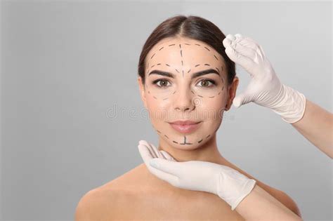 Doctor Examining Woman S Face With Marker Lines For Plastic Surgery