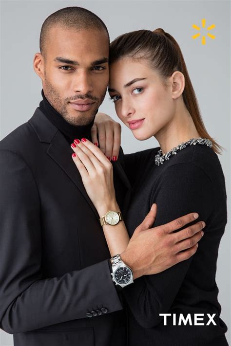 A Man And Woman Embracing Each Other With The Timex Logo In The Back Ground