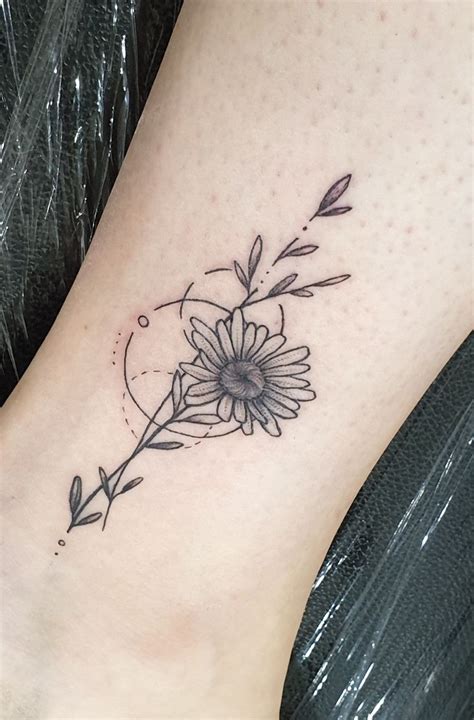 A Flower Tattoo On The Ankle Is Shown In Black And Grey Colors With An