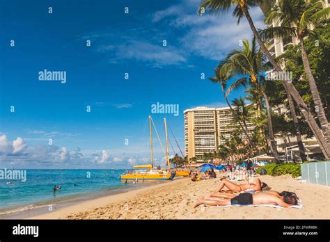 Oahu Hawaii People Enjoying Waikiki Beach With Hotel And Sailboat On