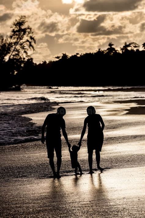 Silueta De La Familia En La Playa En La Puesta Del Sol Imagen De