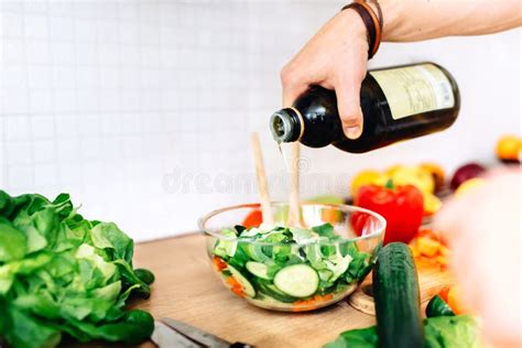 Male Chef Preparing Salad Pouring Virgin Olive Oil On Vegetables Stock