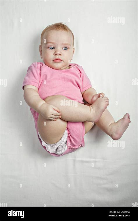 A Baby Girl Lying On Her Back Touching Her Barefoot Curiously Stock