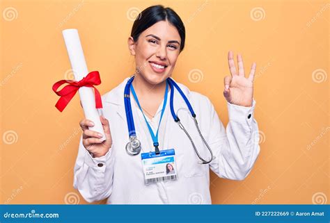 Young Beautiful Doctor Woman Wearing Stethoscope Holding Diploma Degree Graduated Doing Ok Sign