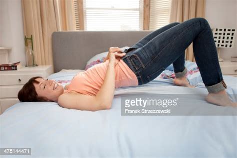 Young Woman Trying To Zip Jeans On Bed Photo Getty Images