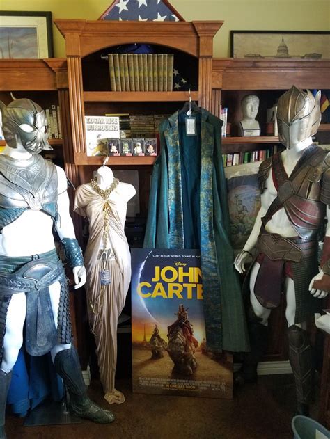 Some Costumes Are On Display In Front Of A Bookcase And Bookshelf Full Of Books