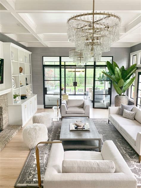 A Living Room Filled With White Furniture And A Chandelier Hanging From