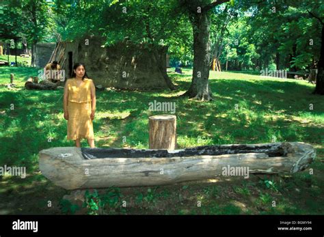Traditional Cherokee Village With Woman In Buckskin Dress Standing Next
