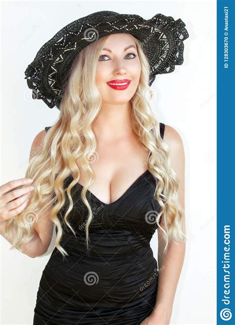belle blonde de jeune femme dans la robe et le chapeau noirs avec decollete photo stock image