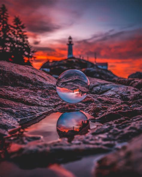 Two Bubbles Floating On Top Of A Rocky Beach Next To A Lighthouse At