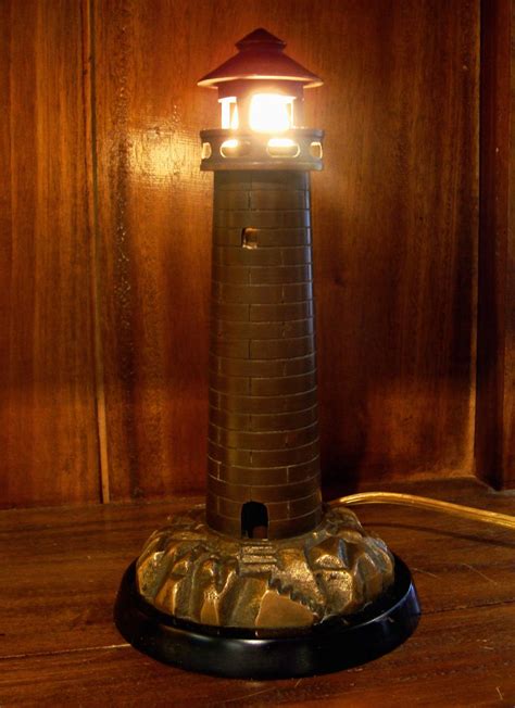 An early 1900's cast brass lighthouse mounted on a black ...