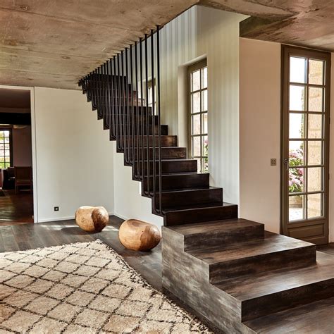 A Stair Case In The Middle Of A Living Room With Two Large Wooden Balls