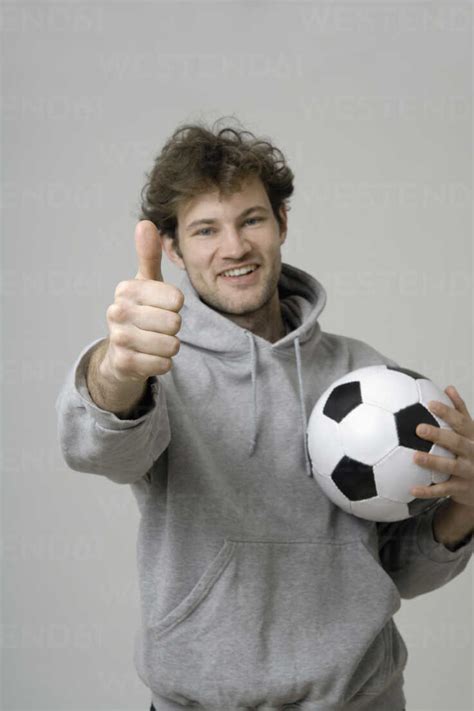 Young Man Holding Soccer Ball And Showing Thumbs Up Stock Photo