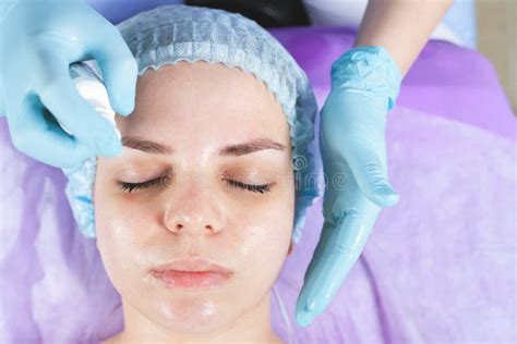 Woman In Spa Salon Receiving Face Treatment With Facial Cream Stock