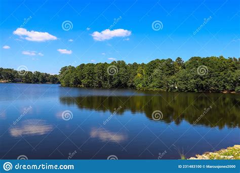 A Gorgeous Shot Of Vast Still Blue Lake Water Surrounded By Lush Green