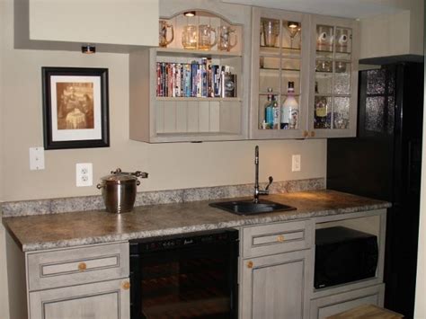 I envision a well lit area that incorporates a wall of storage cabinetry in light gray, additional undercounter drawer storage, a sweet ge refrigerator, kohler sink, microwave, dishwasher, and small hdtv. Rec room wet bar, featuring custom cabinetry, bar sink ...