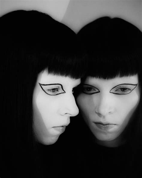 Two Women With Black Hair And Makeup Are Facing Each Other