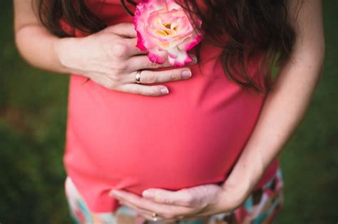 Mujer Embarazada Sujetando Una Flor Blanca Con Los Bordes Rojos Foto