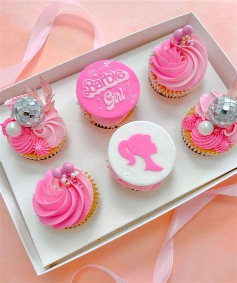 Cupcakes With Pink Frosting And Decorations In A White Box On A Table