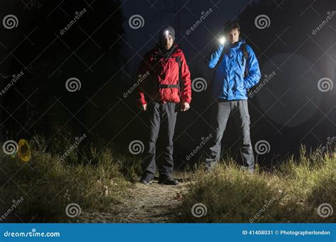 Full Length Portrait Of Male Hikers With Flashlights In Field At Night
