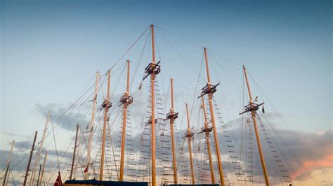 Image Of High Wooden Masts Of Old Ships In Port Against Blue Sky At