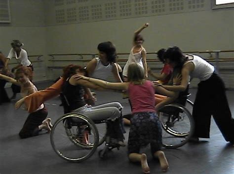 A Group Of People Standing Around Each Other In A Room With Wheelchairs