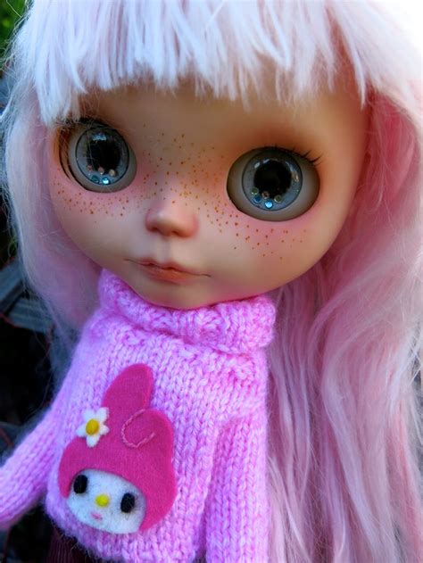 A Close Up Of A Doll Wearing A Pink Sweater With Hello Kitty On Its Chest