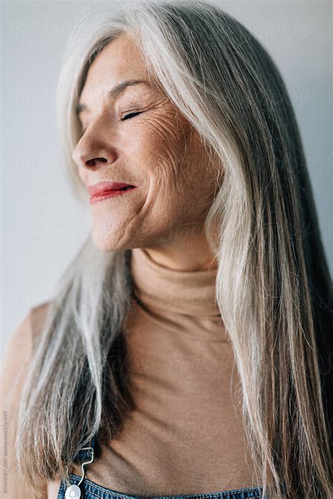 Portrait Of A Smiling Senior Woman With Grey Long Hair By Stocksy