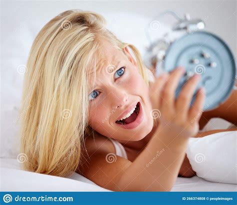 i overslept again upset woman holding her alarm clock with an expression of fright stock