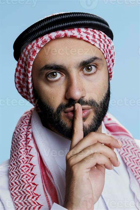 Man Wearing Muslim Headscarf Signaling For Silence With Hushed Finger