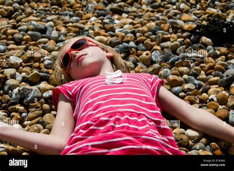 Young Girl Sunbathing On A Pebble Beach Stock Photo Alamy