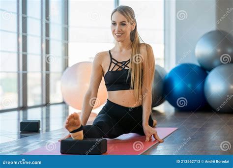 flexible girl demonstrates longitudinal splits with yoga blocks smiling slender woman is