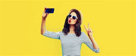 Portrait Of Young Woman Taking Selfie With Smartphone Blowing Her Lips With Red Lipstick Sending