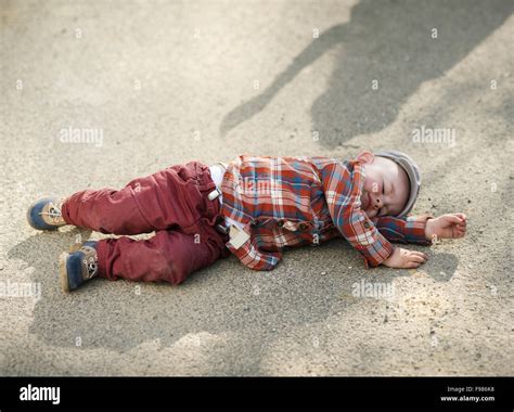 Outdoor Portrait Of Little Boy Crying And Lying Down On The Sidewalk