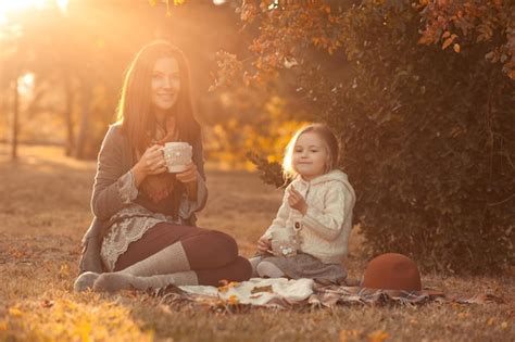 Madre Bebiendo Té Con La Hija Del Niño Sentado A La Luz Del Sol En El