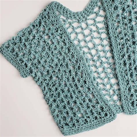 Two Crocheted Sweaters Sitting Next To Each Other