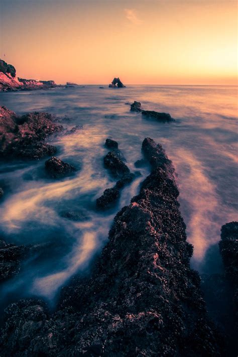 Long Exposure Seascape Photograph Taken During A Vibrant Orange Sunset