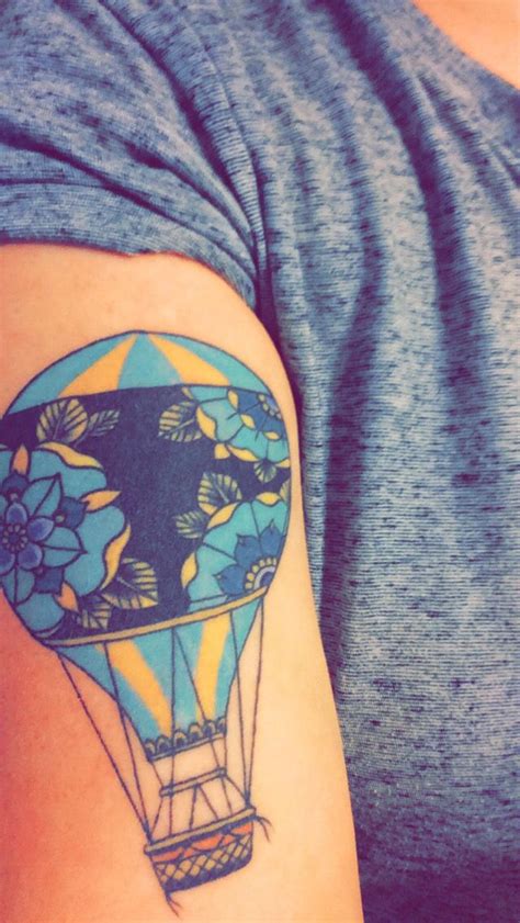 A Hot Air Balloon Tattoo On The Right Side Of The Left Arm With Blue Flowers In It