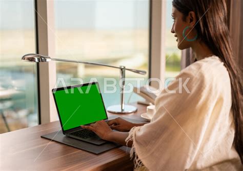 سيدة عربية خليجية سعودية تستخدام حاسوب محمول بشاشة كروما خضراء، اجراء مكالمة فيديو، انجاز