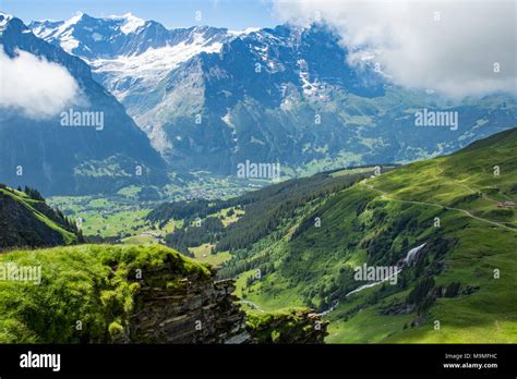Swiss Countryside With Snow Capped Mountains And Waterfalls In