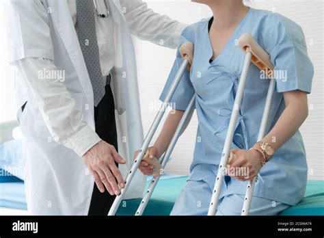 Doctor Takes Care Of Patient In Crutch At Hospital Physical Therapist