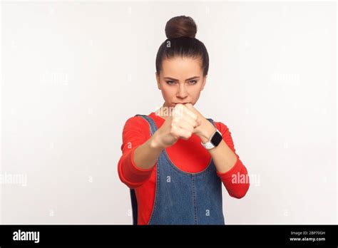 let s fight portrait of determined aggressive confident girl with hair bun in denim overalls