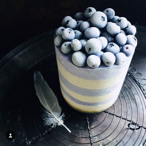 There Is A Cake With Blueberries On It And A Feather Sitting Next To It