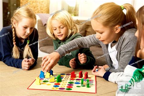 Four Children Playing Ludo In Living Room Stock Photo Picture And