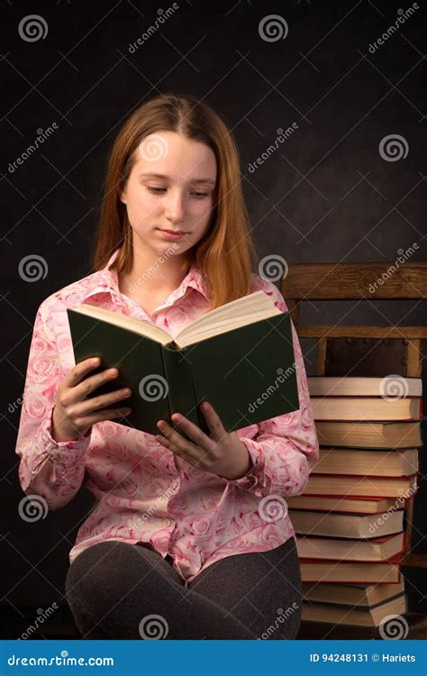 Portrait Of A Teenager Girl Reading Book Near The Stack Of Books Stock