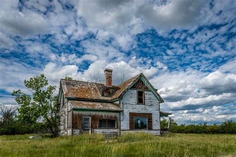 Old Abandoned Prairie Farmhouse With Trees Grass And Blue Sky In