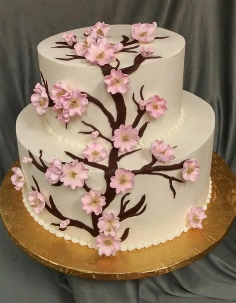 A Three Tiered Cake With Pink Flowers On The Top And Gold Trimmings