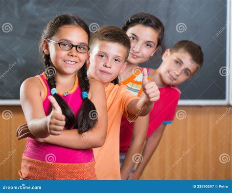 Four Smiling Schoolchildren Standing In Classroom Stock Image Image