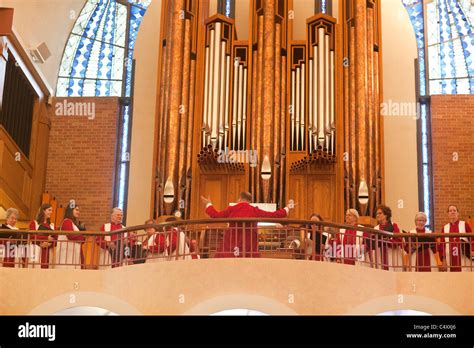 Director Leads Church Choir In Song In Front Of Large Pipe Organs